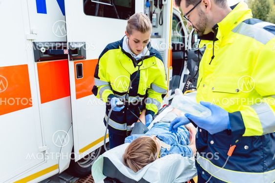 Paramedics measuring blood pressure of injured boy