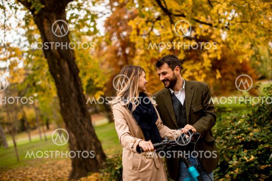 Young couple in the autumn park with electrical bicycle