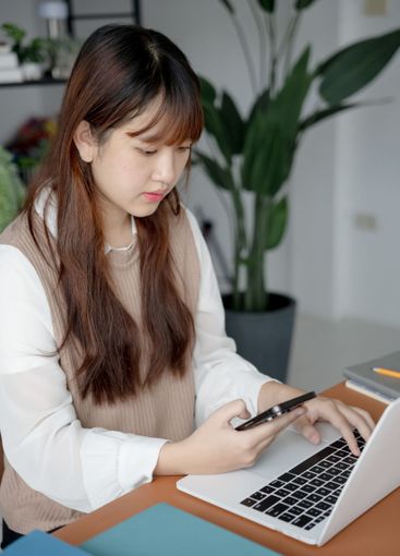 Asian woman using laptop to study student engaged in...