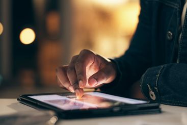 Black man, tablet and working at night in office with...