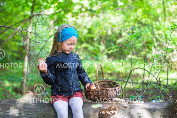 Little girl gathering mushrooms in autumn forest