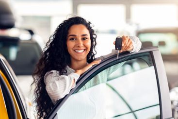 Cheerful brunette woman holding key, buying new car,...