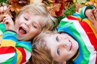 Two little kid boys laying in autumn leaves in colorful...