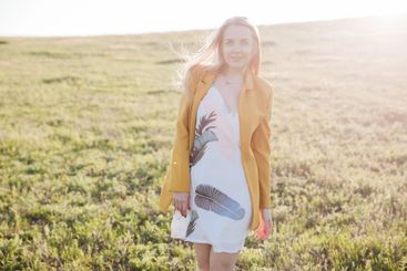 Beautiful blonde woman in summer dress walking in...