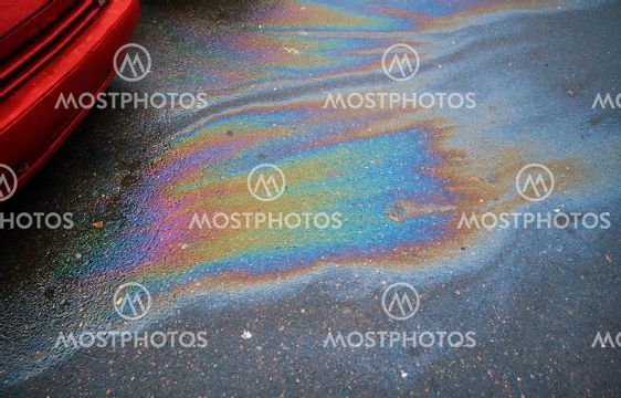 Colorful gas stain on wet asphalt. Oil stain caused by a...