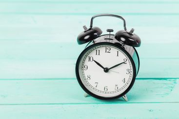 Black vintage alarm clock on wooden table