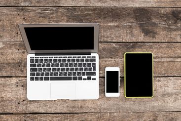 Laptops, tablets, and smartphones arranged on a wooden...
