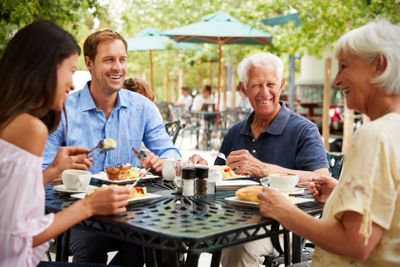 Senior Parents With Adult Children Enjoying Meal At...