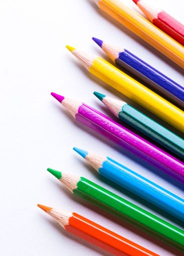 Vibrantly colored pencils lined up on a clean white...