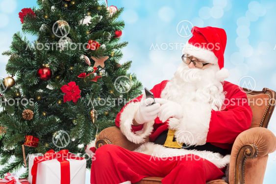 santa claus with smartphone and christmas tree