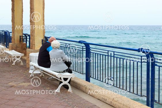 Elderly couple sitting on the sea in the early morning