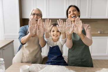 Laughing granny young mommy little girl show palms in flour