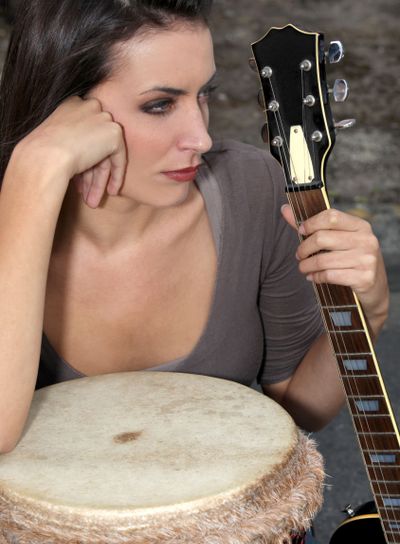 Moody brunette holding guitar and bongo
