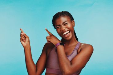 Black woman, fitness and smile in studio with pointing,...