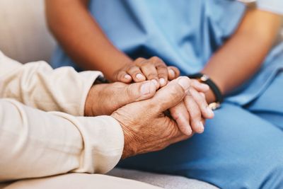 Nurse, patient and holding hands in nursing home for...
