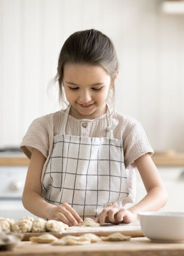 Little girl busy in home kitchen preparing homemade...