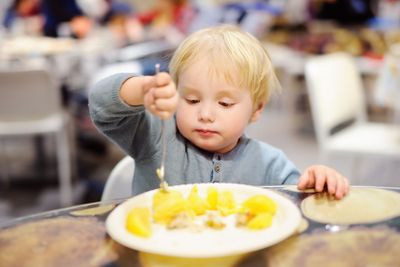 Toddler boy eating in cafe 
