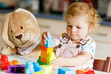 Adorable toddler girl with favorite plush bunny playing...