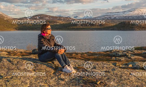 Woman sitting on rock in sunset