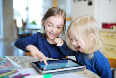 Two little sisters playing with a digital tablet