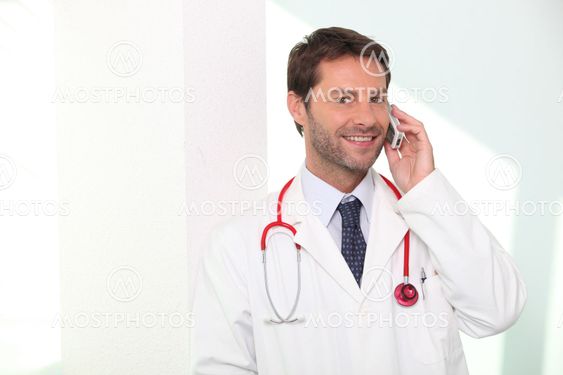 A doctor phoning and smiling.