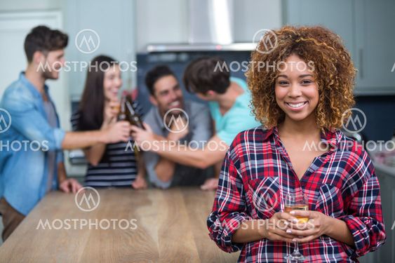 Smiling woman holding wine while friends in background