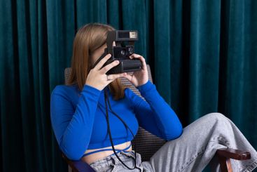 A cute teenager in casual clothes takes pictures sitting...