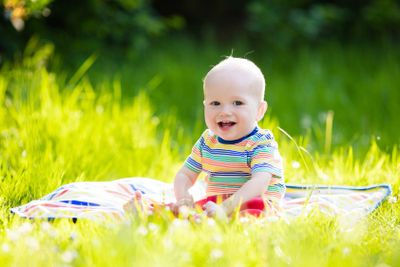Baby boy with apple on family garden picnic