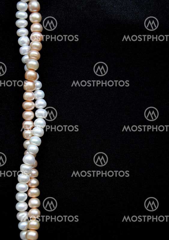 White and pink pearls on the black silk background