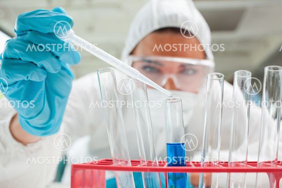 Close up of a protected scientist dropping liquid in a test tube