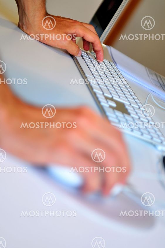 lose-up of male hand on mouse while working on laptop