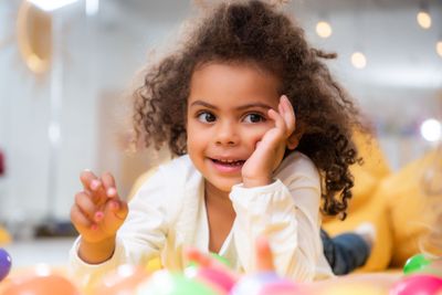 smiling adorable african american child lying on carpet...