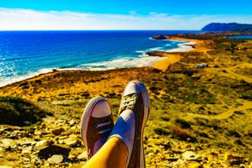 Female feet against coast landscape, Spain.