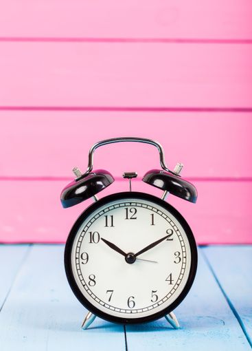 Black vintage alarm clock on wooden table