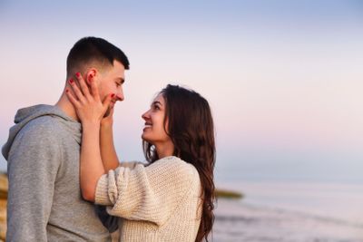 Young couple at rocky seacoast in sunset