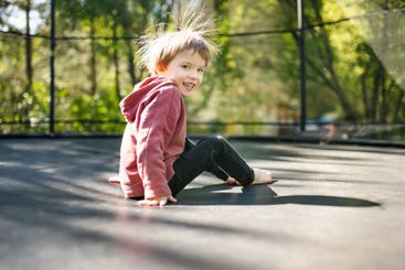 Little boy jumping on a trampoline in a backyard on warm...