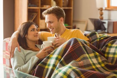 Young couple cuddling on the couch under blanket