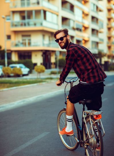 Stylish man in sunglasses riding a bike on city street