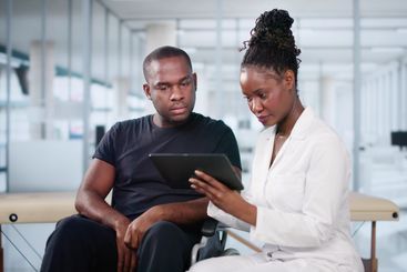 Happy African Doctor With Male Patient In Hospital
