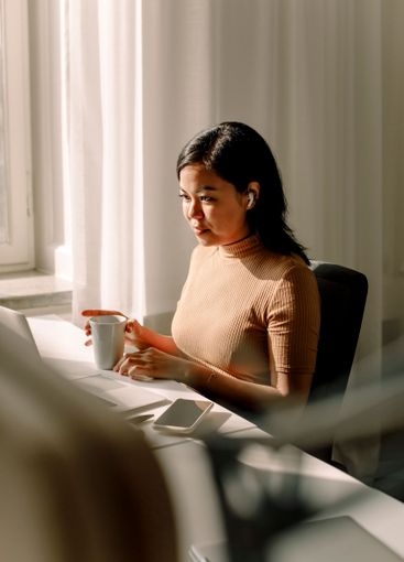 Confident businesswoman sitting with coffee cup and...