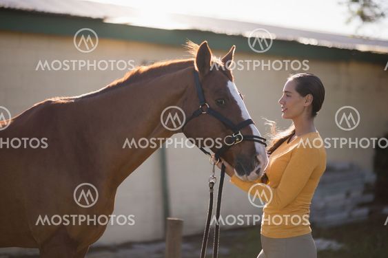 Female jockey with horse at barn