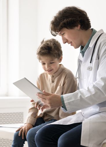 Smiling young man physician consult little patient using...