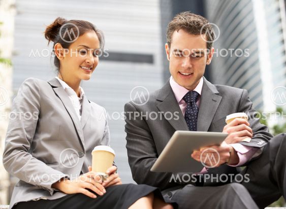 Businessman And Businesswoman Using Digital Tablet Outside Office