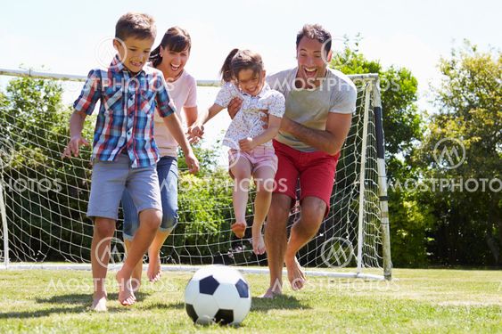 Family Playing Football In Garden Together