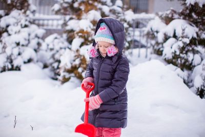 Little girl play with snow shoveling on a winter day