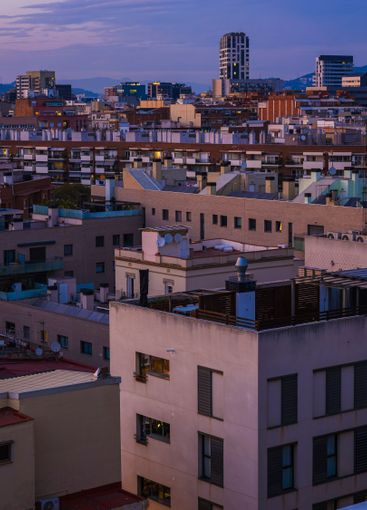 Evening cityscape of Barcelona shows buildings with dusk...