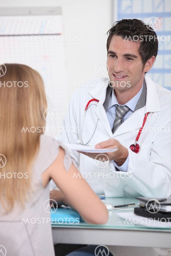 Doctor handing a prescription to a female patient