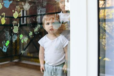 A boy paints with palms on the window. Quarantine