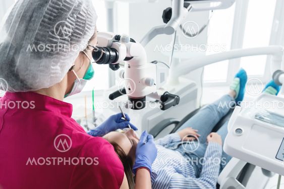 A female professional dentist examines a female patient...