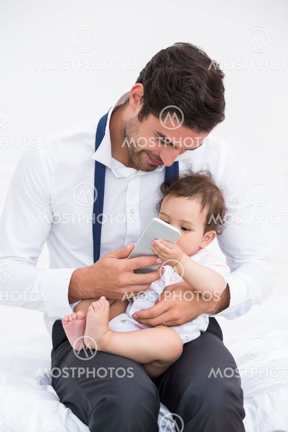 Smiling father holding mobile phone with baby